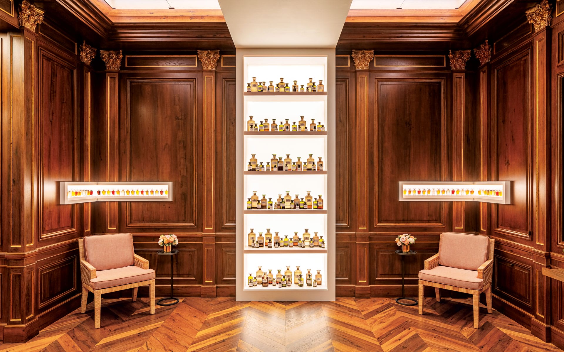 Luxurious wooden-paneled room with shelves displaying a collection of whisky bottles and two upholstered chairs.