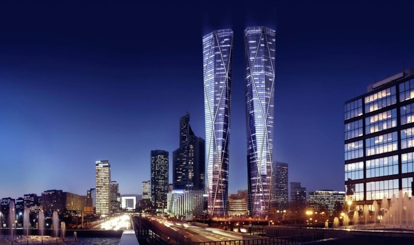 Night view of a cityscape with modern skyscrapers and a bright skyline reflecting on a river.