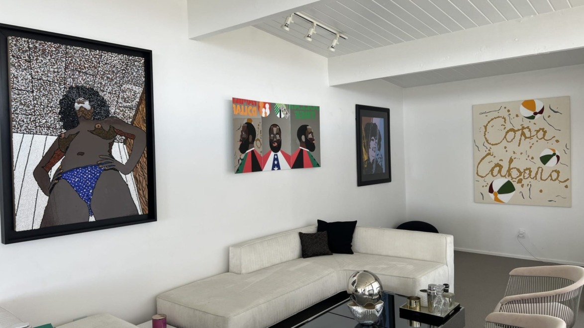 modern art pieces hanging on white walls in a contemporary living room with white sofas and a reflective coffee table