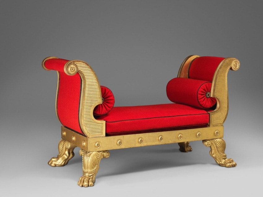 Red and gold neoclassical settee with ornate lion paw feet and scroll arms against a gray background.