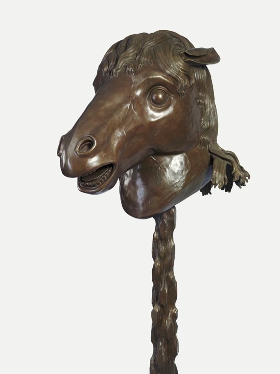 Bronze sculpture of a horse head with detailed mane and expressive eyes against a plain background.