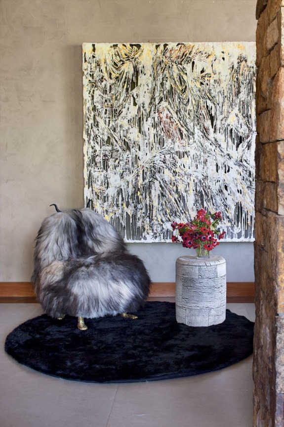 A vestibule off the living room contains a large Diana al-Hadid painting, a Haas Brothers Beast chair from R & Co., and a Peter Lane ceramic stool.