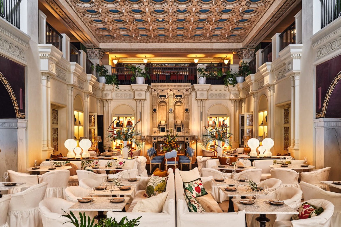 Luxurious restaurant interior with elegant decor, plush seating, intricate ceiling, and ambient lighting creating a warm atmosphere.