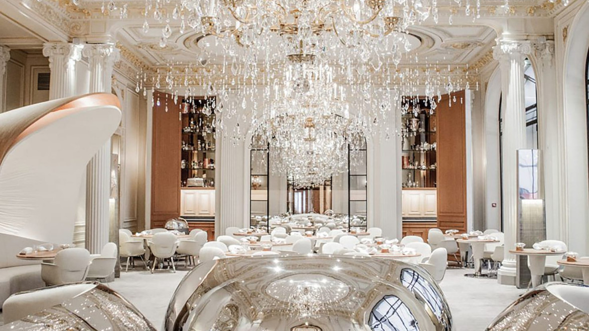 Luxurious dining room with grand chandeliers, elegant white decor, and reflective silver spheres creating a sophisticated ambiance.