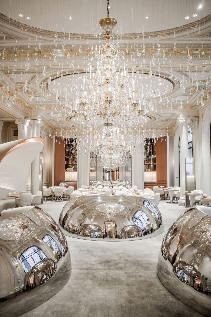 Luxurious restaurant interior with ornate chandeliers, elegant decor, and reflective silver domes creating a sophisticated ambiance.