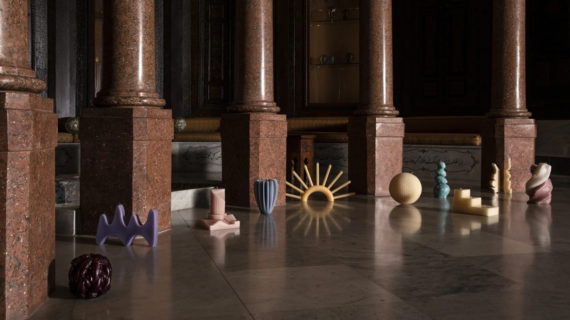 Abstract sculptures displayed on a marble floor in a dimly lit room with large stone pillars.