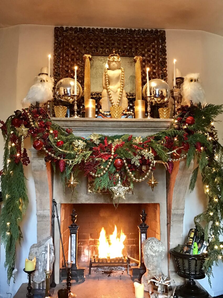 festive fireplace adorned with garland, candles, and gold decorations, with a warm fire burning in the hearth