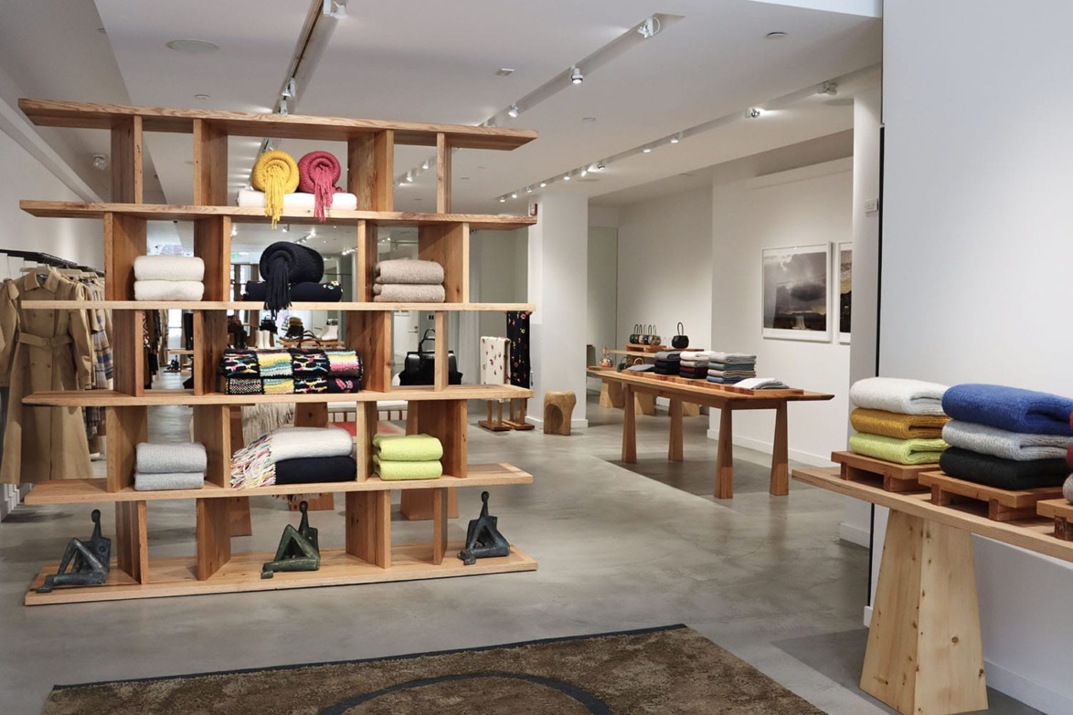 Modern store interior with wooden shelves displaying folded blankets and other home goods.