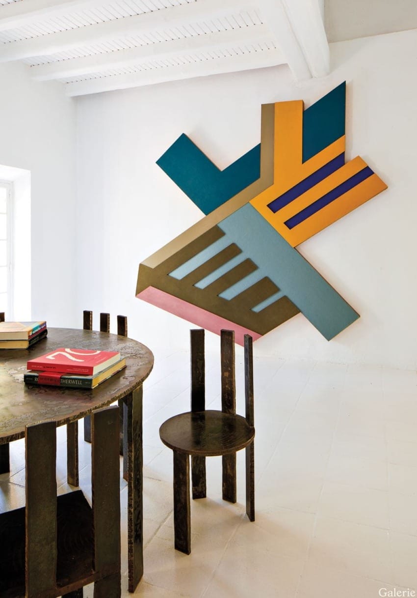 Colorful geometric wall art in modern room with dark wooden table and chair set on light floor.