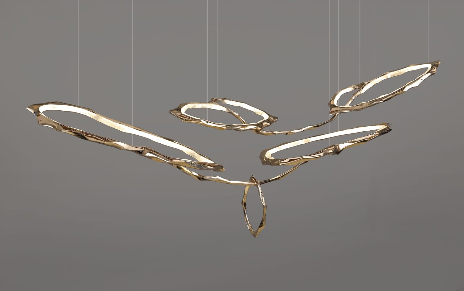 Modern gold abstract ceiling light fixture against gray background