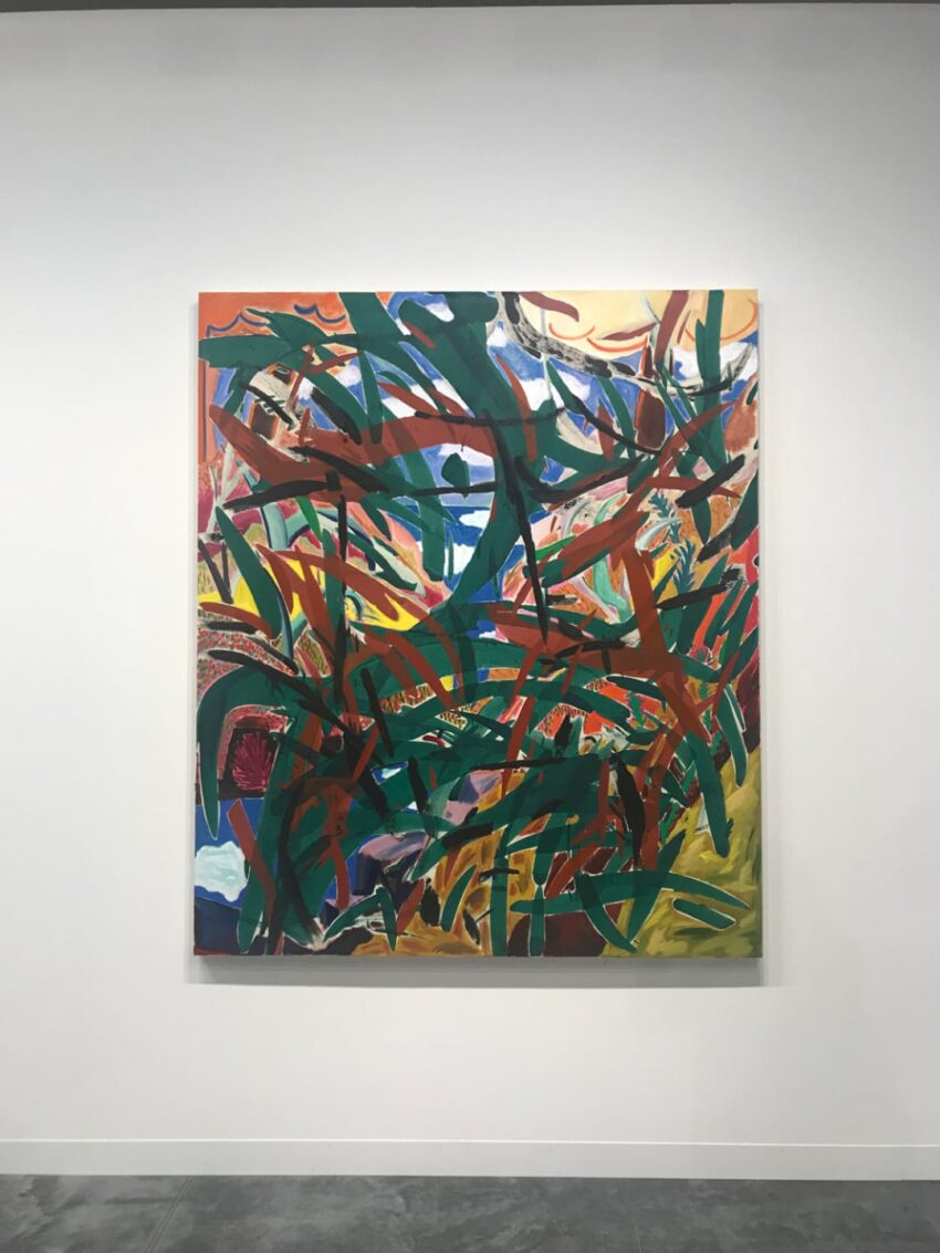 Colorful abstract painting with bold, intersecting brushstrokes in green, red, and blue on a gallery wall.