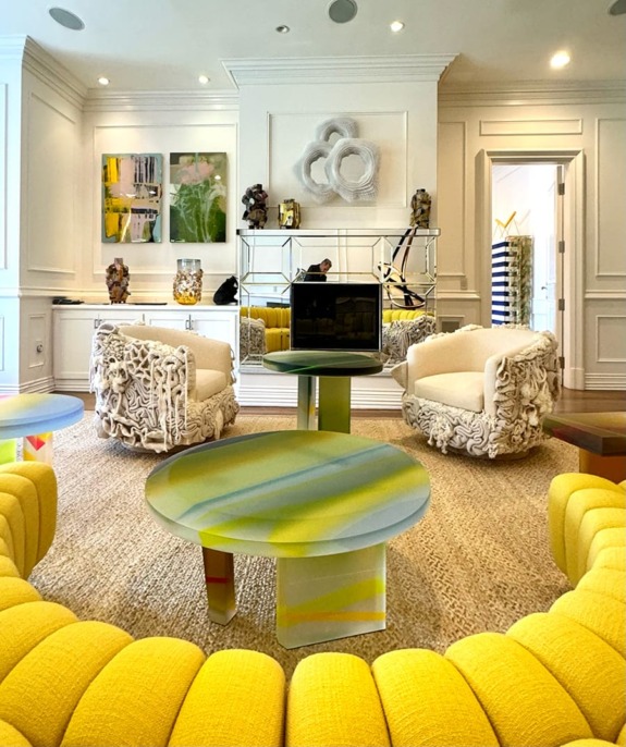 Stylish living room with yellow sofas, modern art, decorative chairs, and vibrant round coffee table.