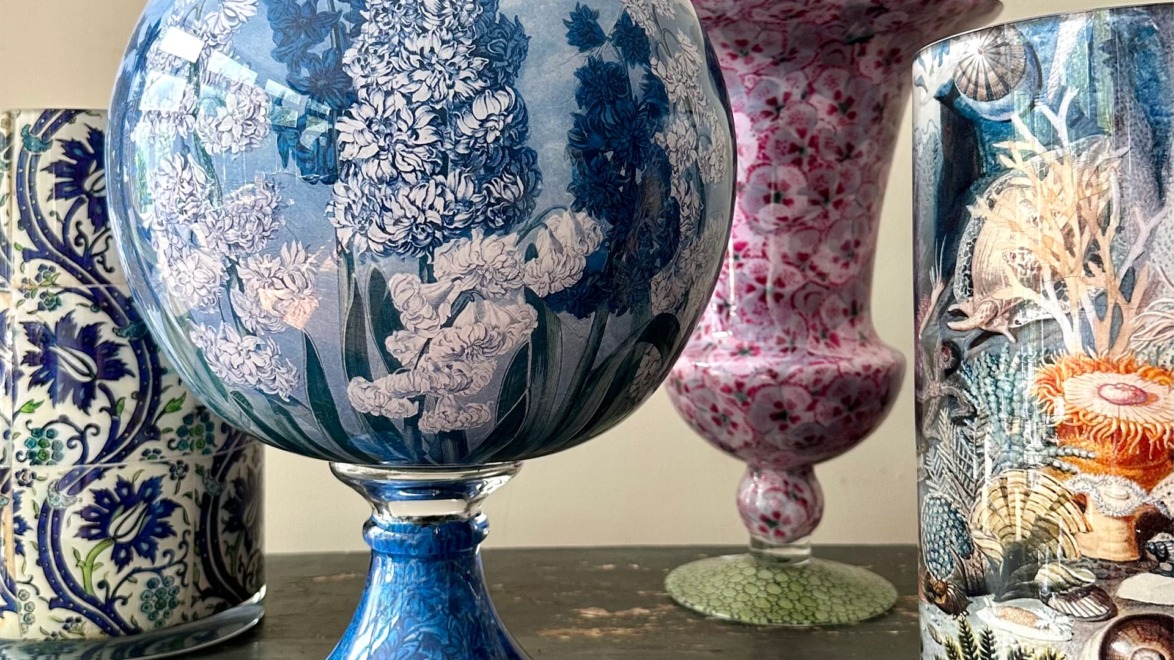 Ornate glass vases with intricate floral and marine designs displayed on a wooden surface.