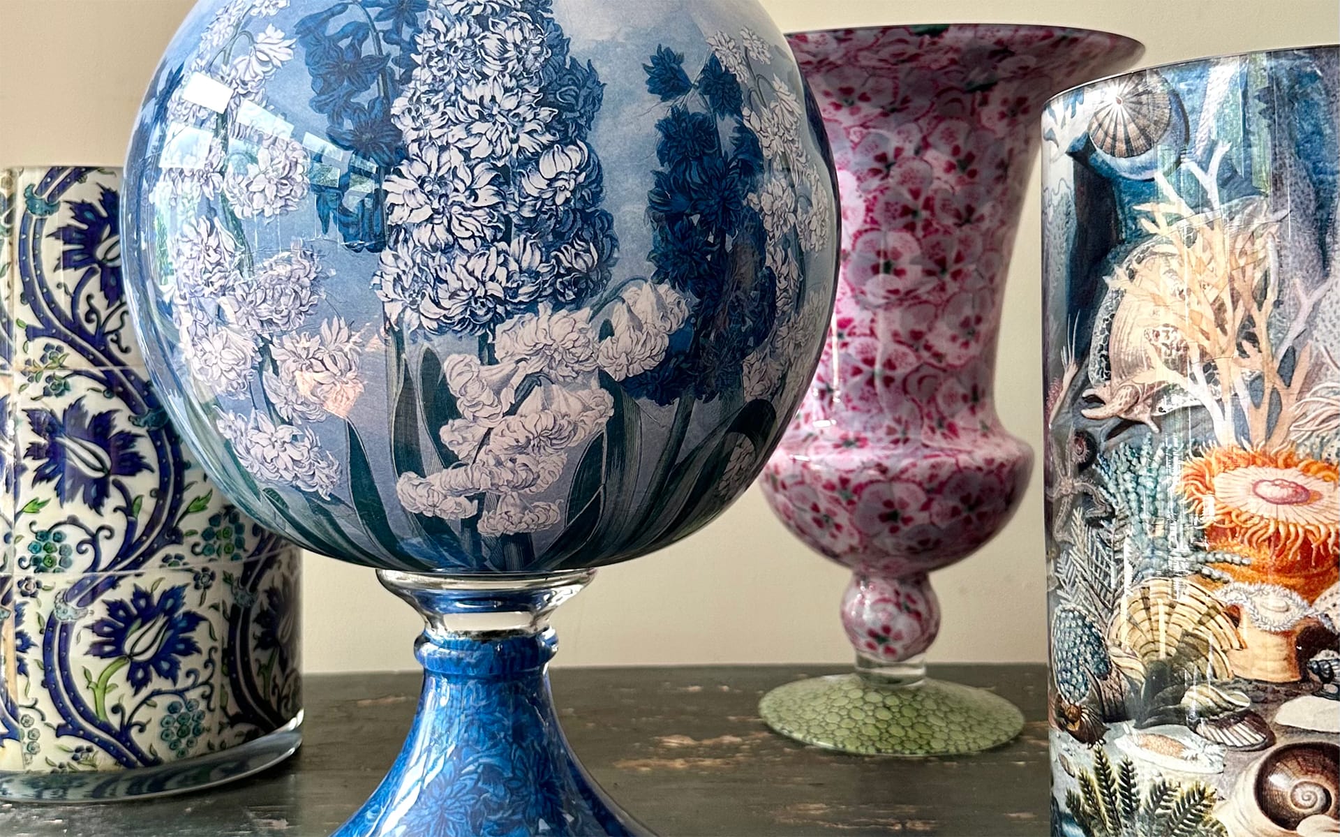 Ornate glass vases with intricate floral and marine designs displayed on a wooden surface.