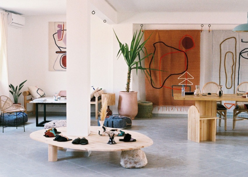 Modern interior design shop with abstract art, wooden furniture, potted plant, and natural light filling the space.