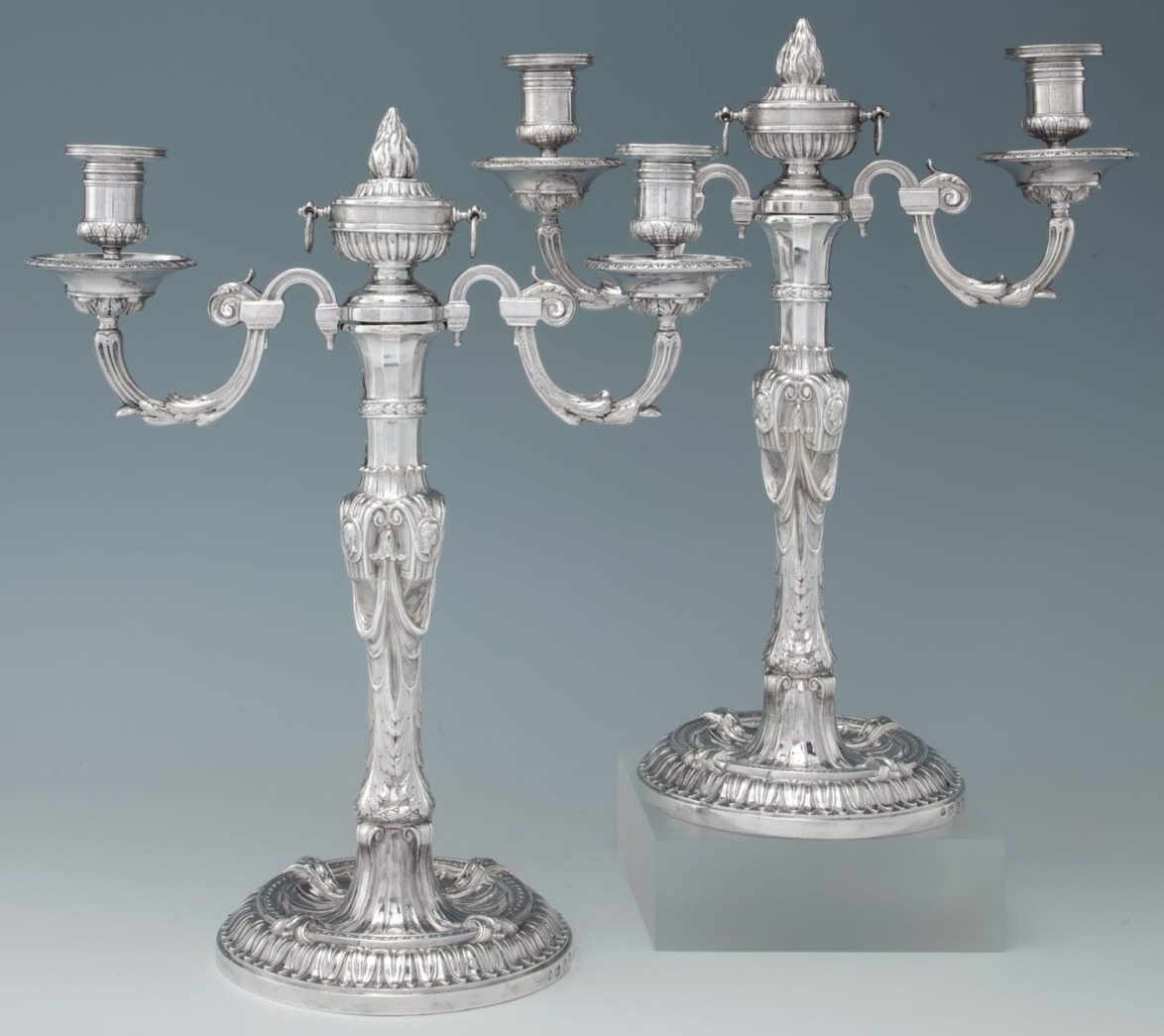 Silver candelabra pair with ornate design featuring three candle holders each against a blue background.