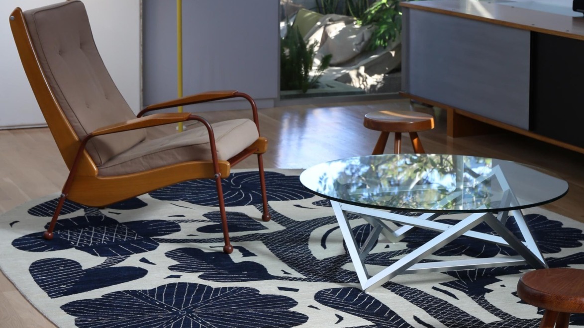 modern living room with a brown chair glass coffee table and patterned rug