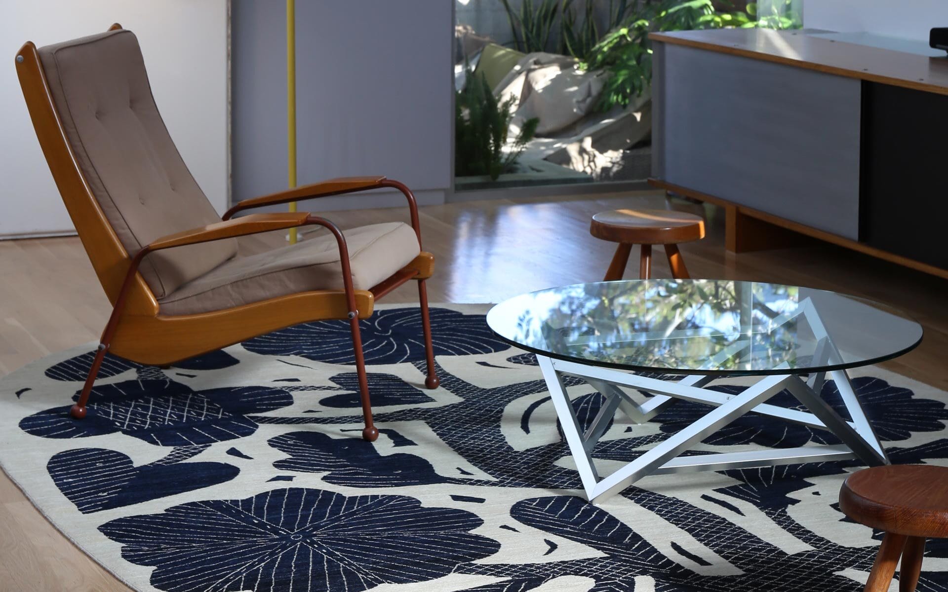 modern living room with a brown chair glass coffee table and patterned rug