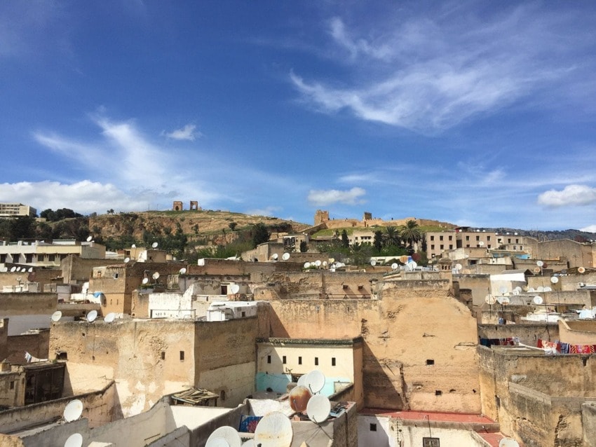Historic Moroccan cityscape with satellite dishes on rooftops under a clear blue sky.