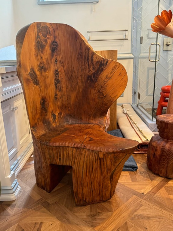 Wooden chair with unique grain patterns, placed in a room with parquet flooring and white cabinetry in the background.