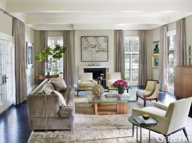 Elegant living room with large windows, neutral furniture, and decorative art pieces on the walls.