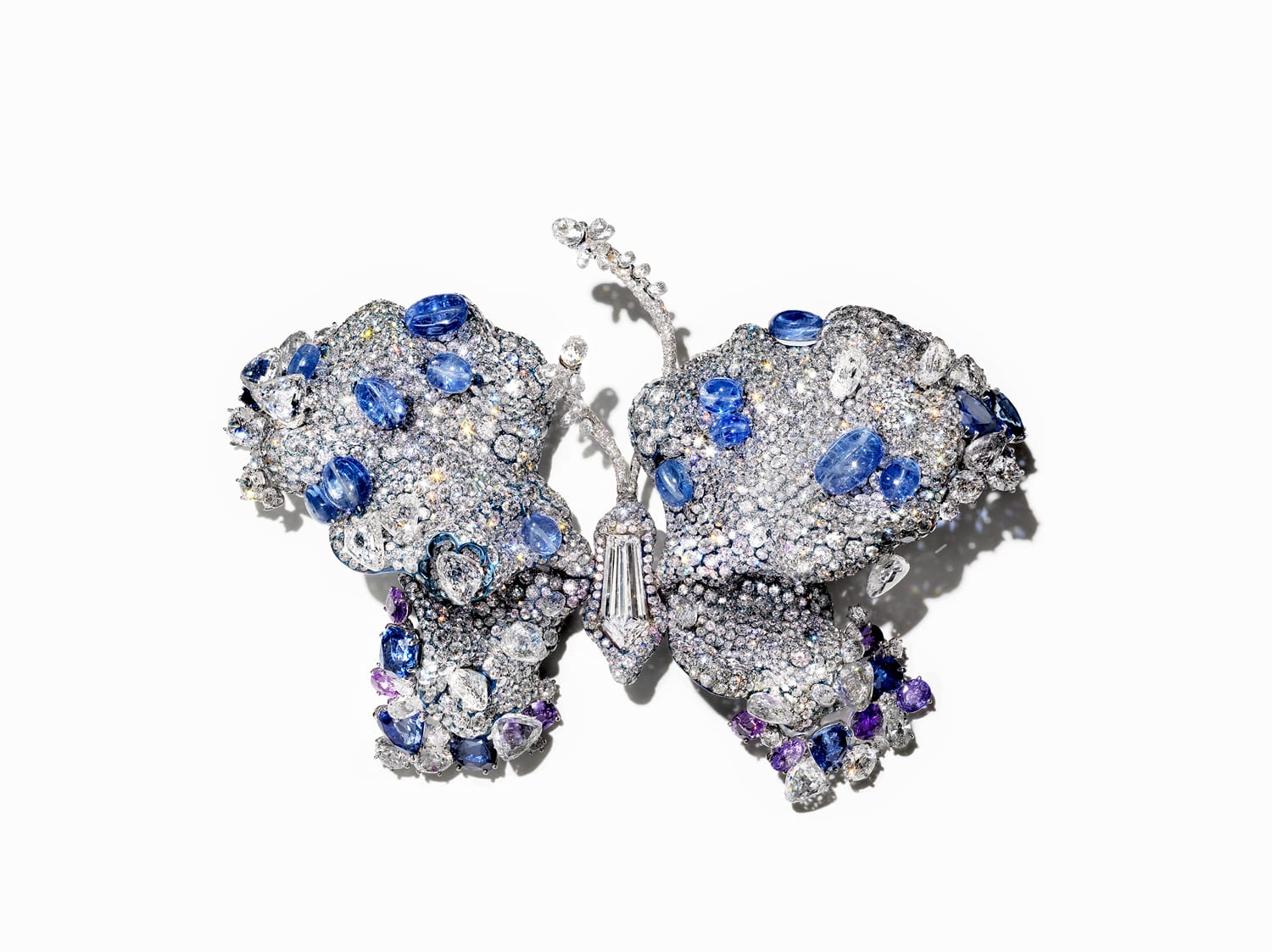 Butterfly brooch adorned with various gemstones, including sapphires and diamonds, on a plain white background.