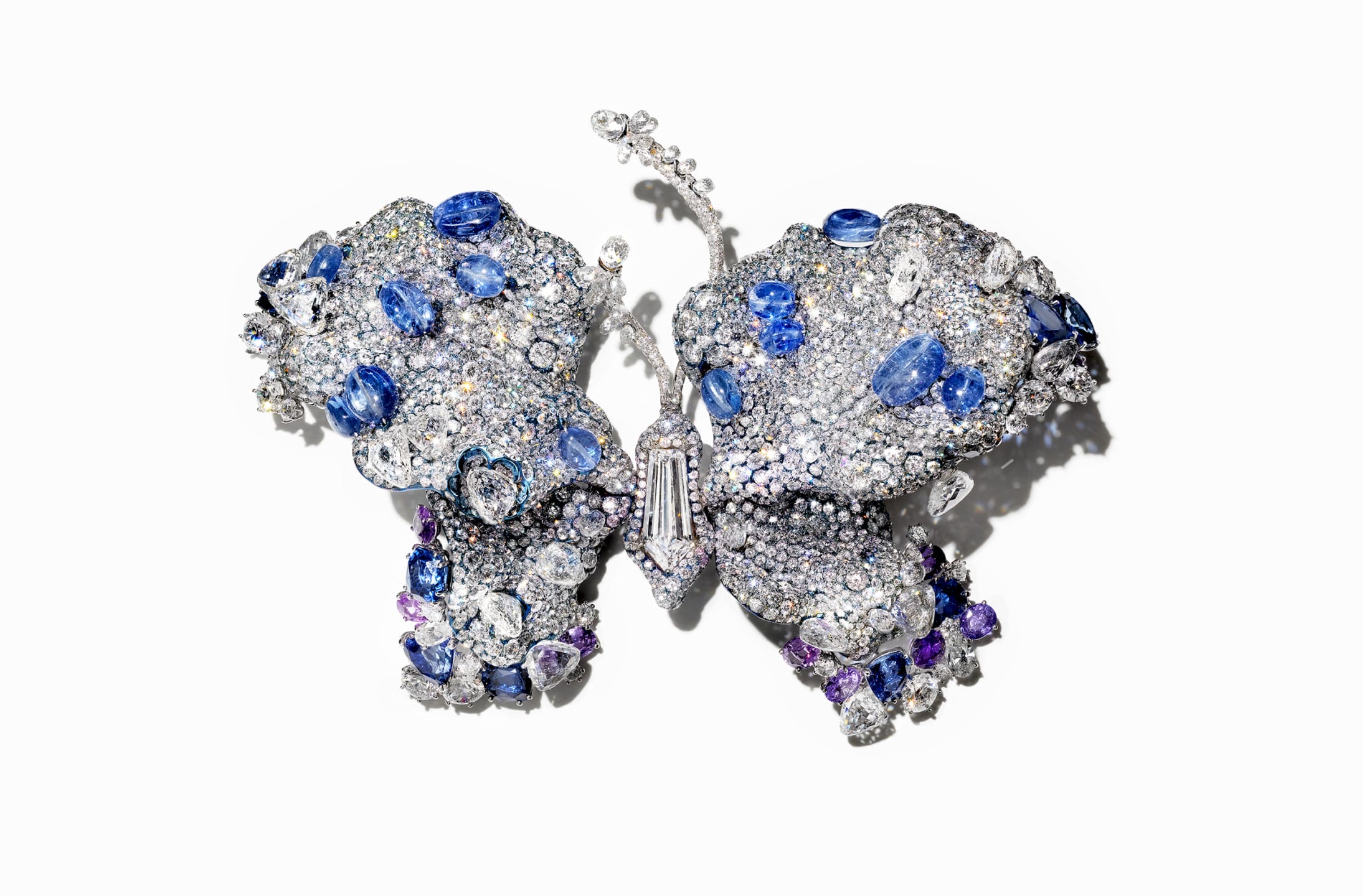 Jeweled butterfly brooch with sparkling gemstones in shades of blue and silver on a plain white background.