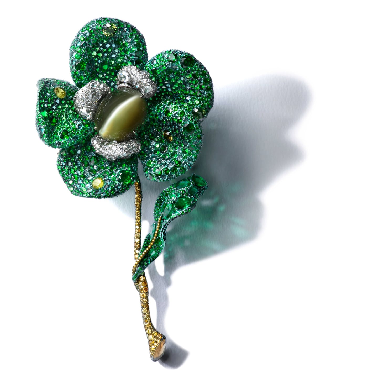 Green and silver jeweled flower brooch with detailed petals and a pearl center on a white background.