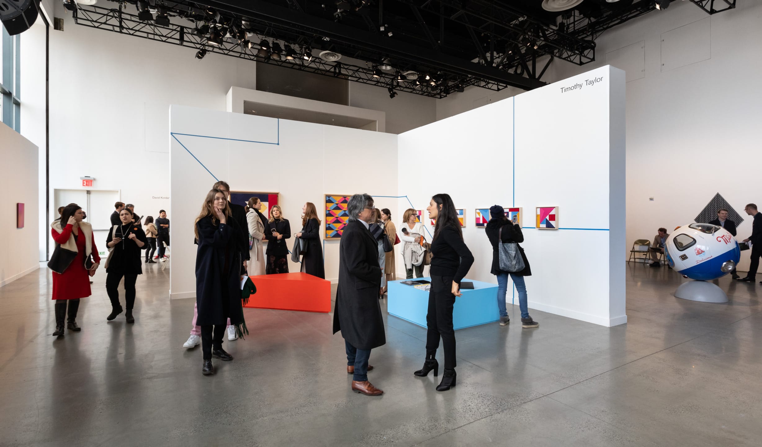 People viewing art installations in a contemporary gallery with modern decor and artwork on display.