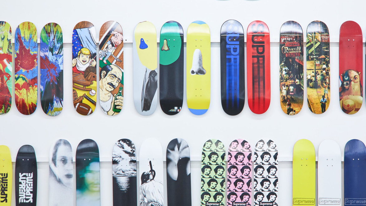 Collection of colorful and patterned skateboard decks displayed on a white wall.