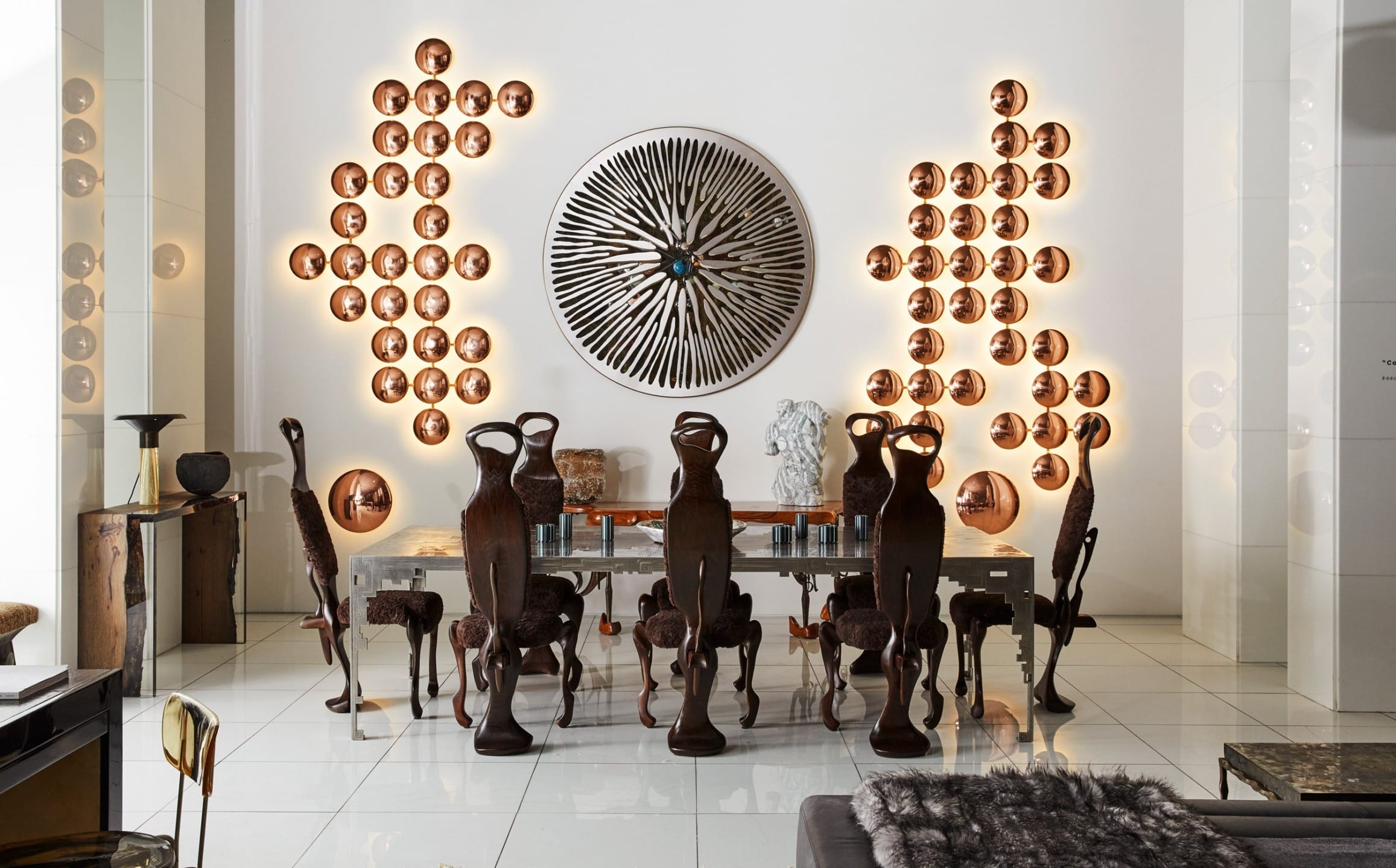 Dining room with unique wooden chairs, decorative plates on walls, and a large, circular patterned artwork in the center.