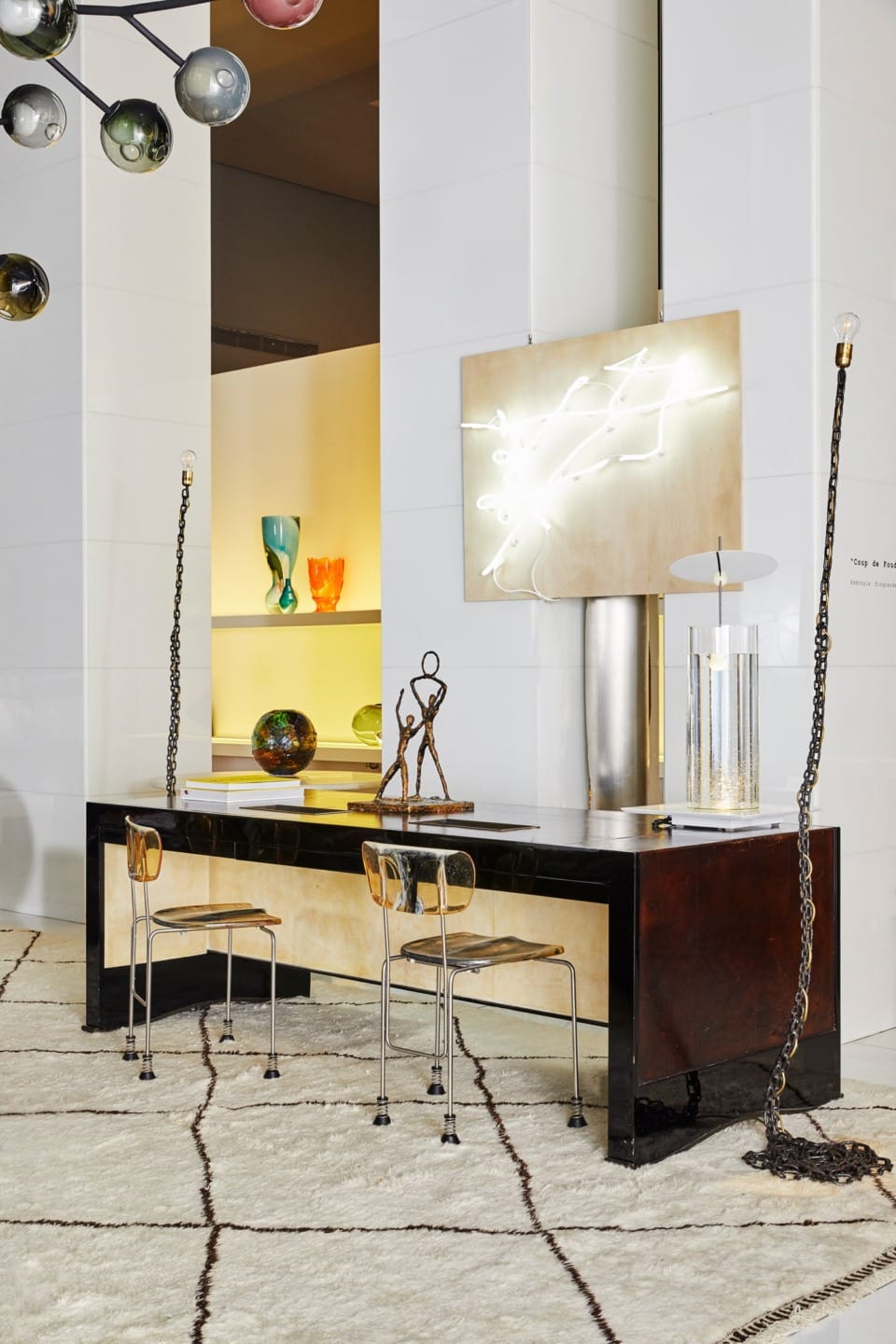 Contemporary room with abstract sculptures, modern chairs, and unique lighting fixtures on and above a stylish desk.