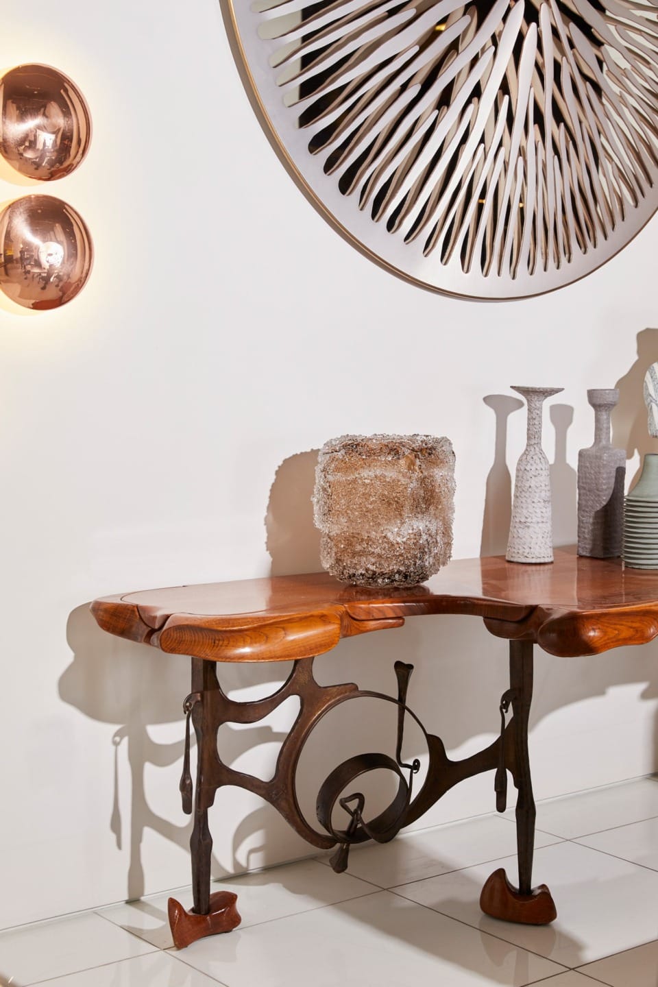 Eclectic dining room with unique wooden table, textured decor, abstract wall art, and warm copper lighting accents.