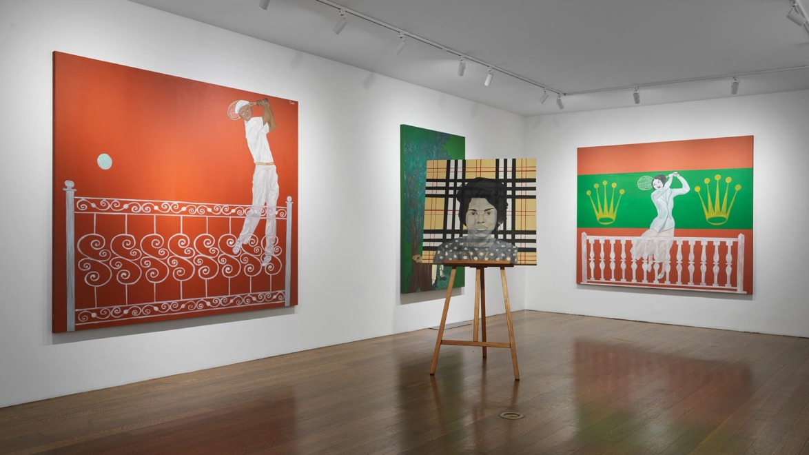 Art gallery with colorful paintings on walls and framed artwork on an easel in the center of the room.