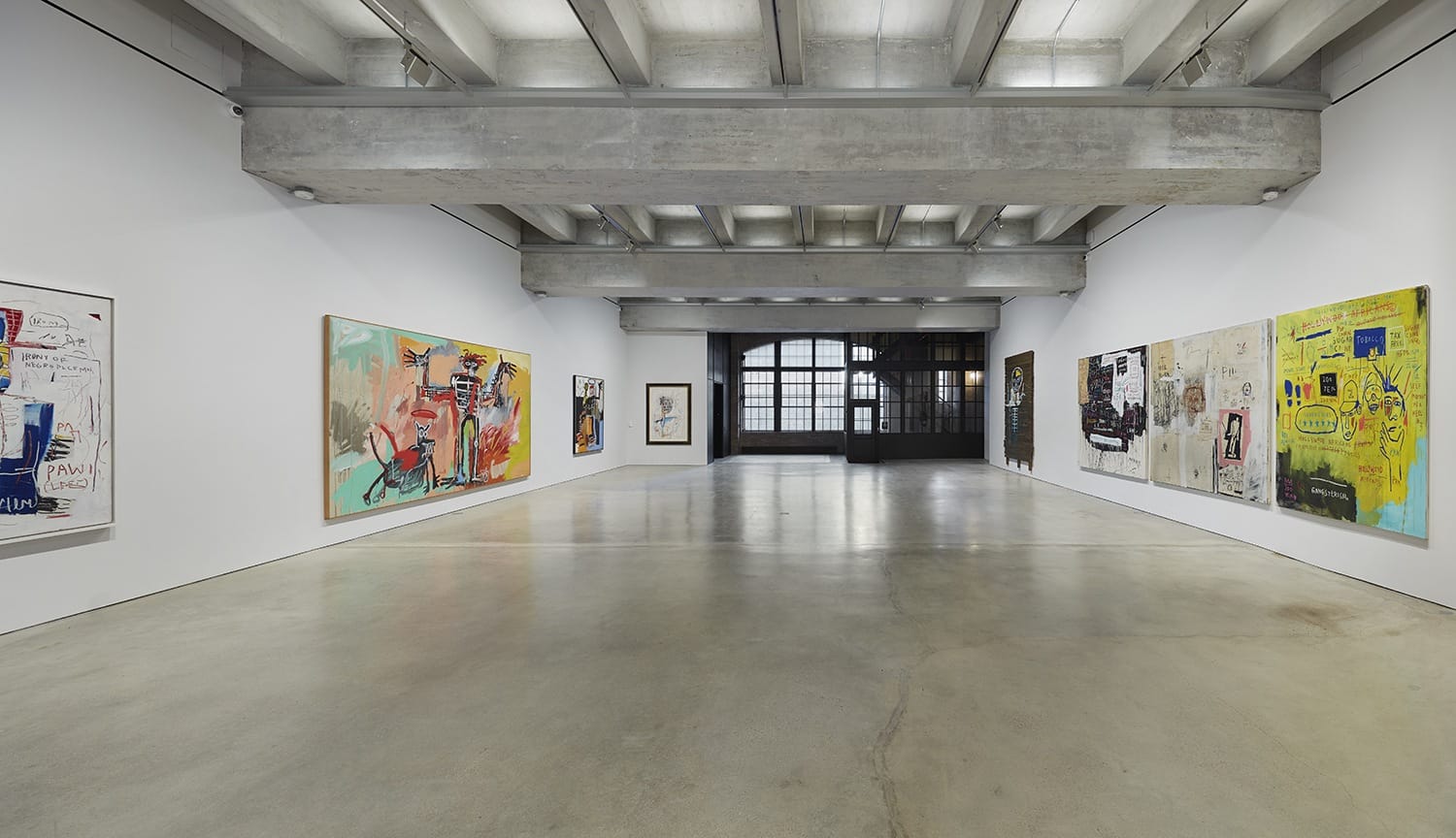 Art gallery with abstract paintings on white walls and a concrete ceiling, showcasing a modern and minimalistic design.