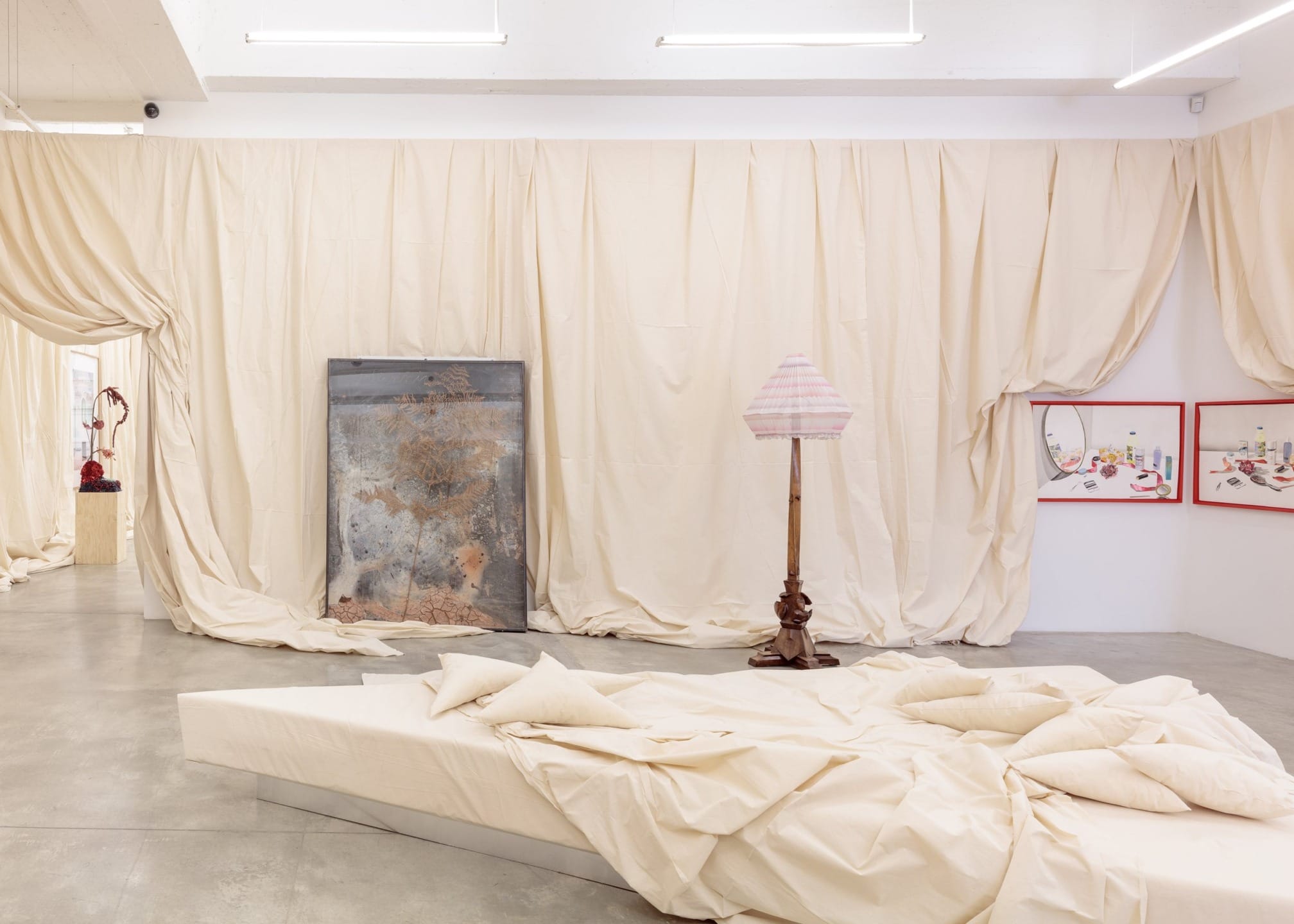 art gallery with contemporary installation including fabric-covered walls, abstract paintings, and a vintage standing lamp