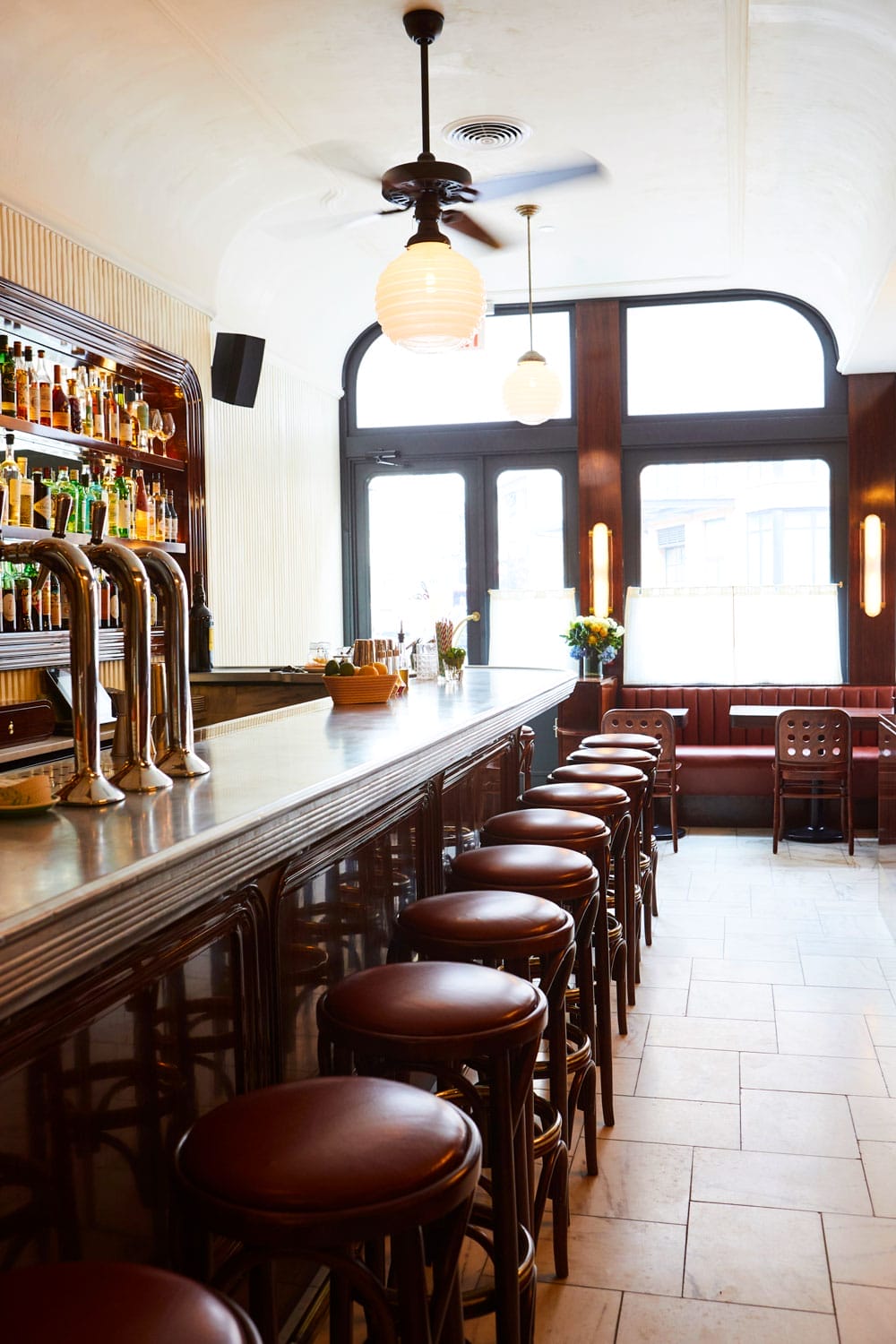 Cozy bar interior with wooden stools, a stocked liquor shelf, and vintage-style lighting.