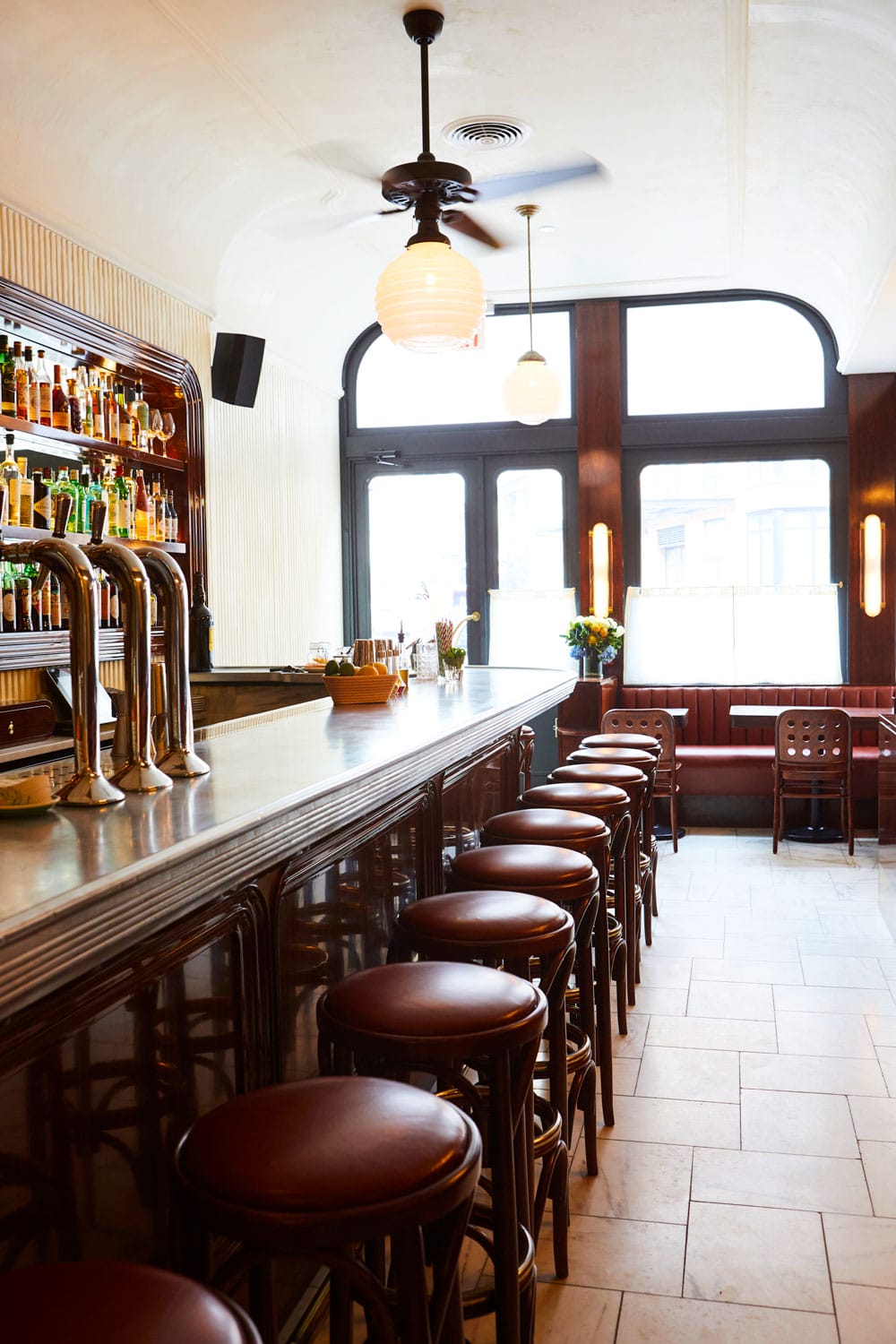 Cozy bar interior with wooden stools, a stocked liquor shelf, and vintage-style lighting.
