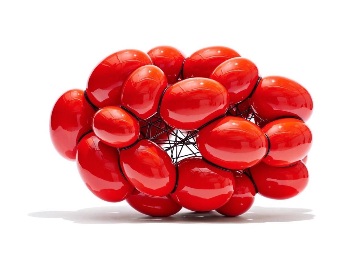 Abstract sculpture made of interconnected shiny red oval shapes on a white background.