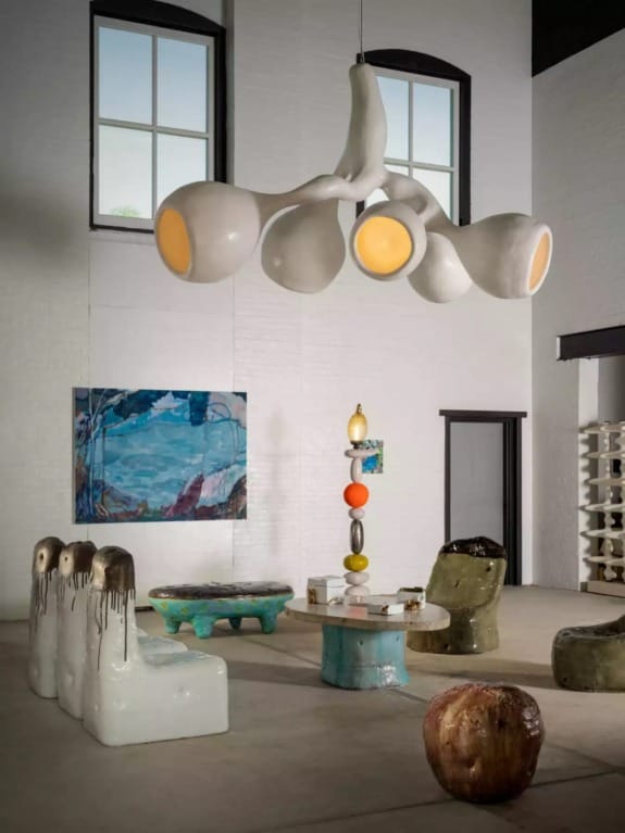 Contemporary art gallery with abstract furniture, bold ceramic pieces, and large modern light fixture.