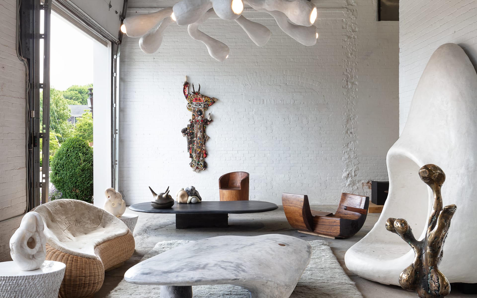 Modern art gallery interior with abstract sculptures, unique furniture, and a textured wall-hanging.