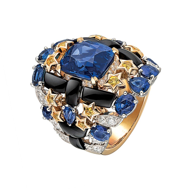 Intricate ring featuring blue sapphire, black and gold accents, and star-shaped details on a gold band.