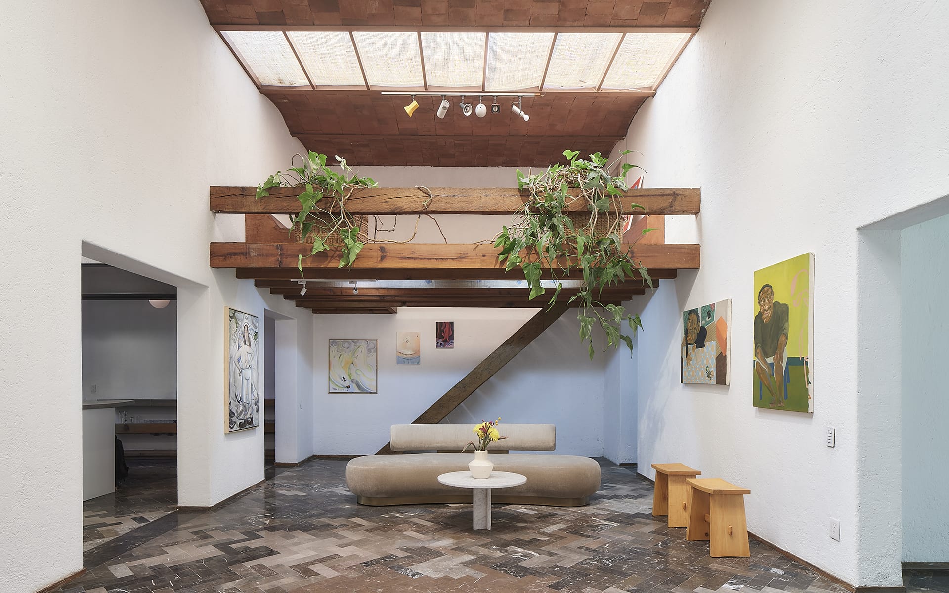 modern living room with wooden beams, indoor plants, contemporary art, beige sofa, coffee table, and herringbone floor
