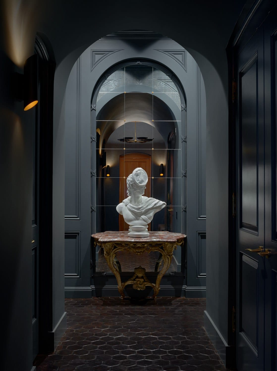 Bust statue in an elegant hallway with dark walls and intricate table