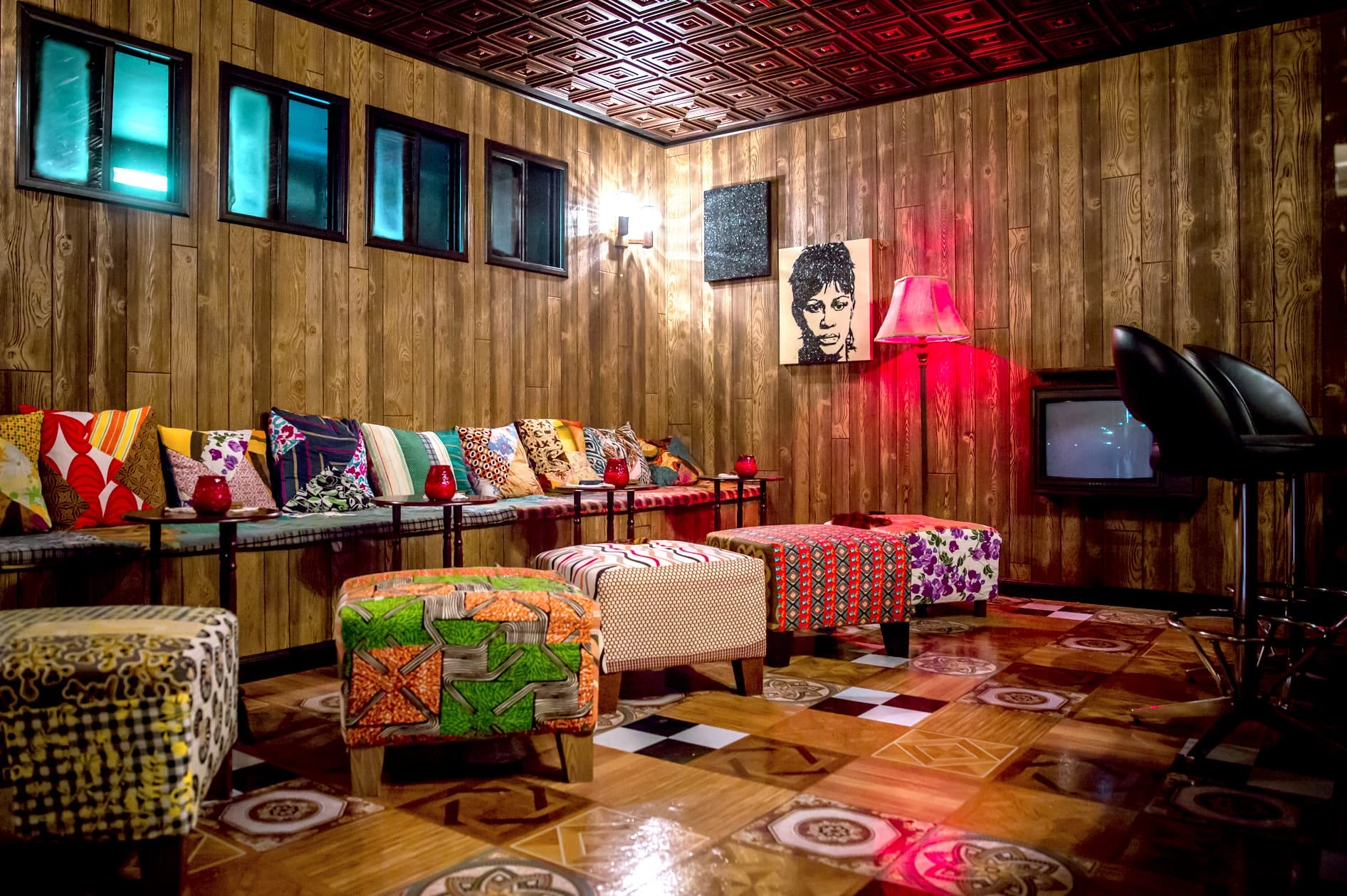 Cozy vintage room with colorful patterned furniture, wooden walls, a retro TV, and artistic decor.