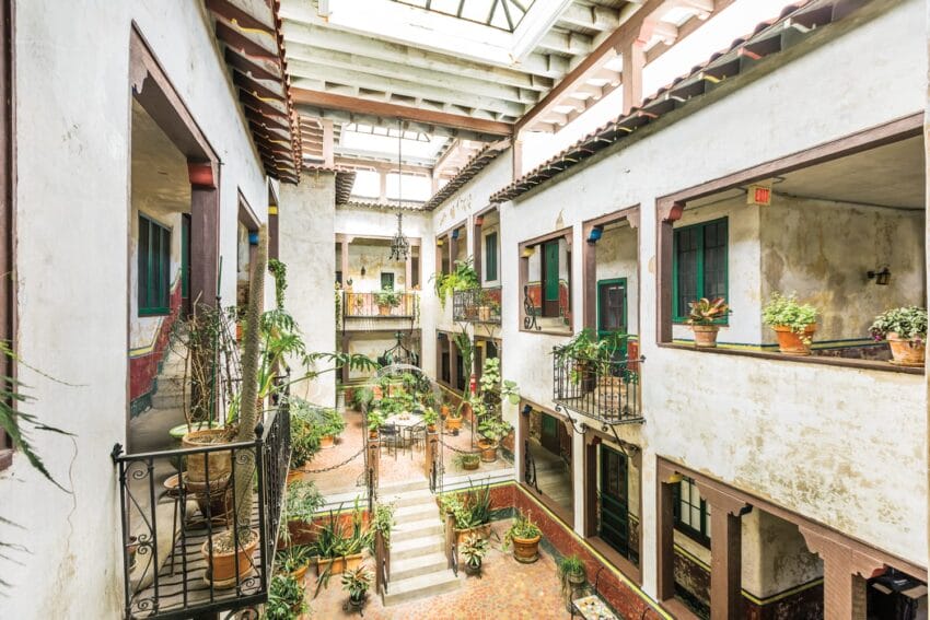 Historic Mediterranean-style courtyard with balconies, terracotta tiles, potted plants, and a skylight ceiling.