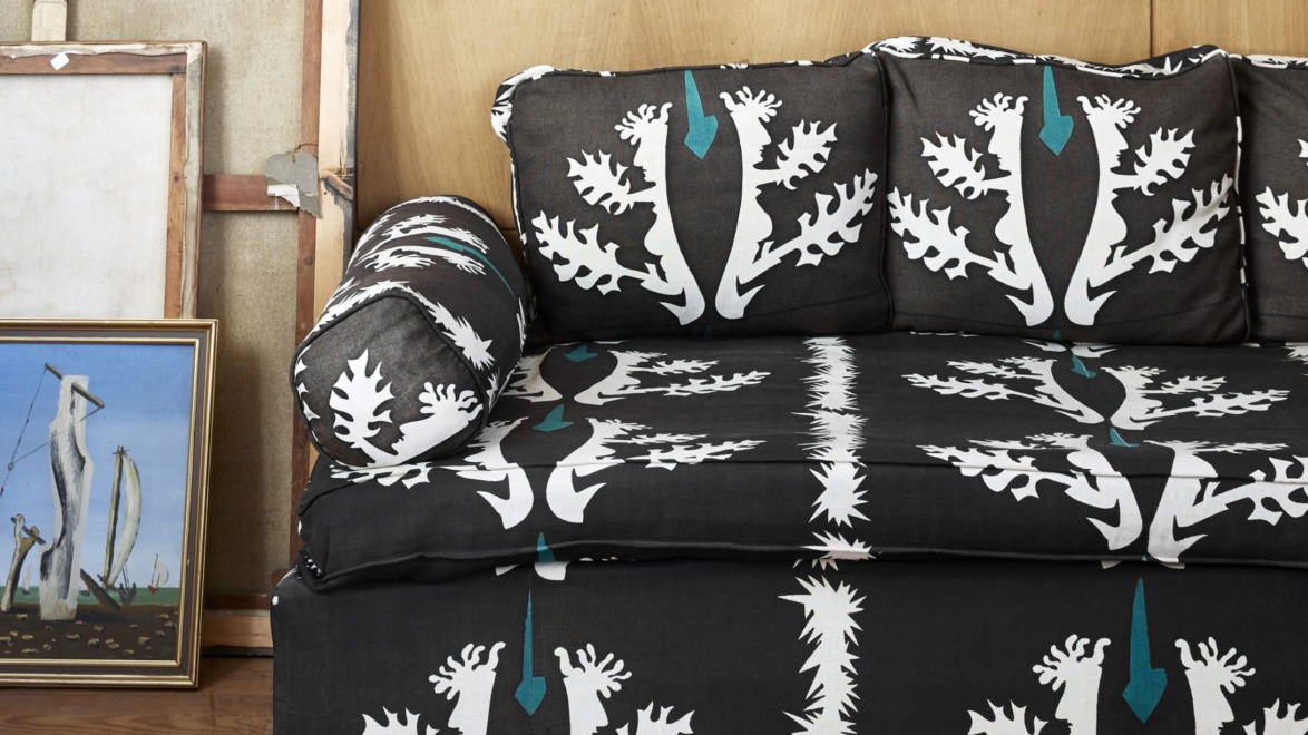 Black and white patterned couch with matching cushions next to a painting of abstract figures.