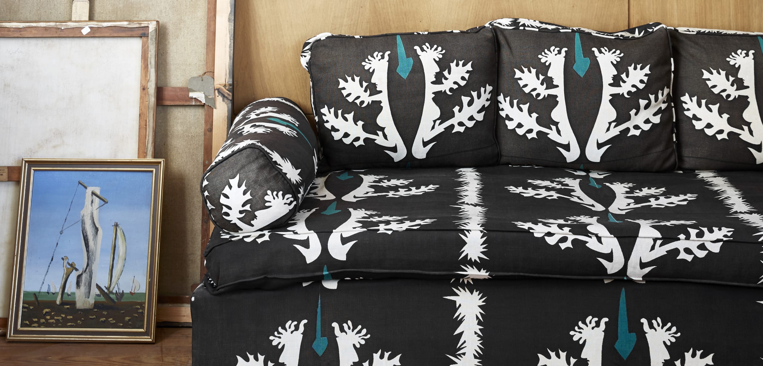 Black and white patterned couch with matching cushions next to a painting of abstract figures.