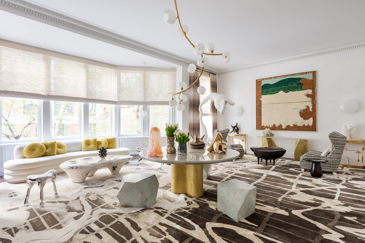 Modern living room with abstract art, unique furniture, and large windows with natural light.