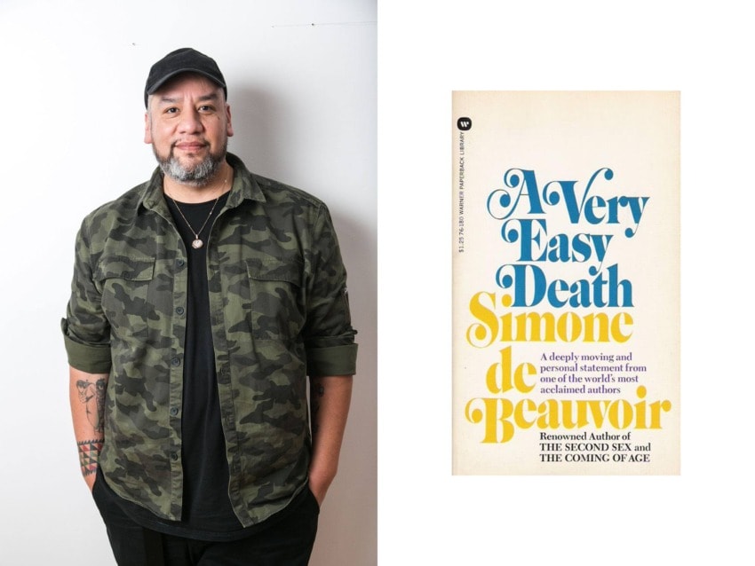 Person in a camo shirt stands smiling next to a book titled "A Very Easy Death" by Simone de Beauvoir.